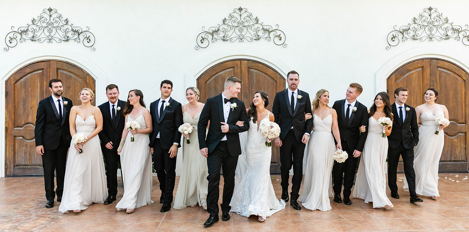 Bridal party laughing as they walk. Bride and groom with bridal party