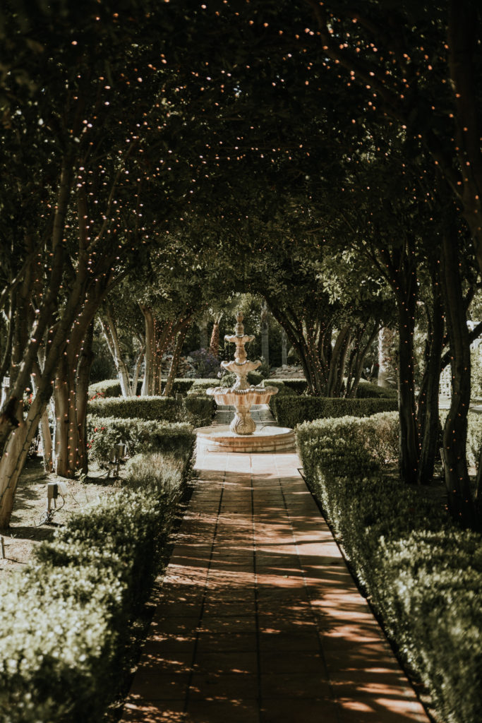 Tuscan fountain in an outdoor wedding setting with surrounding twinkle lights. 